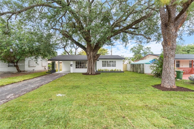 ranch-style home with stucco siding, an attached carport, aphalt driveway, a front yard, and fence