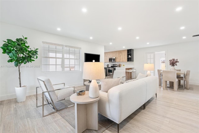 living area featuring visible vents, baseboards, light wood-type flooring, and recessed lighting