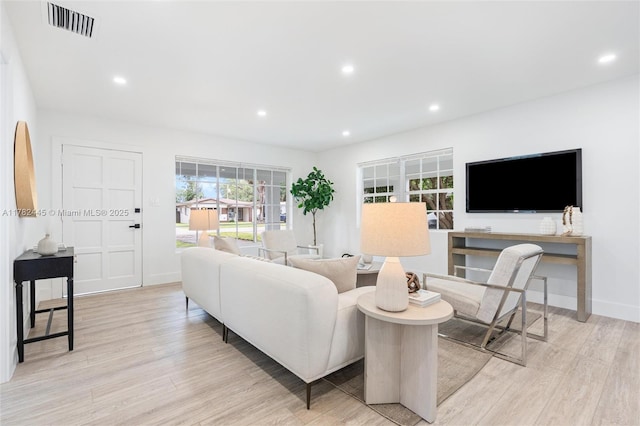 living room featuring baseboards, light wood-style flooring, visible vents, and recessed lighting