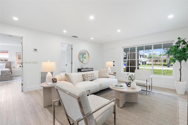 living area with light wood-type flooring, baseboards, a wealth of natural light, and recessed lighting
