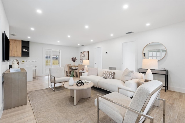 living area with light wood-style flooring, visible vents, and recessed lighting