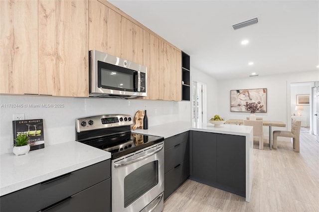 kitchen featuring a peninsula, visible vents, modern cabinets, stainless steel appliances, and light brown cabinetry