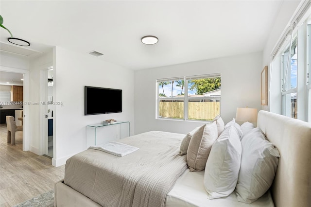 bedroom featuring light wood-type flooring, baseboards, and visible vents
