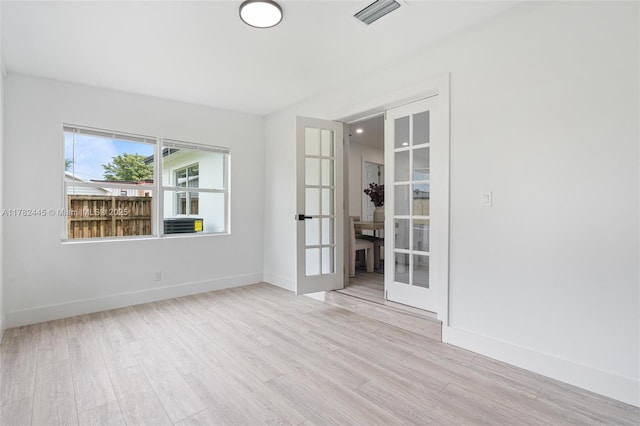 empty room with french doors, baseboards, visible vents, and wood finished floors