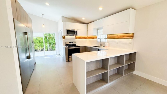 kitchen with modern cabinets, a sink, stainless steel appliances, decorative backsplash, and lofted ceiling