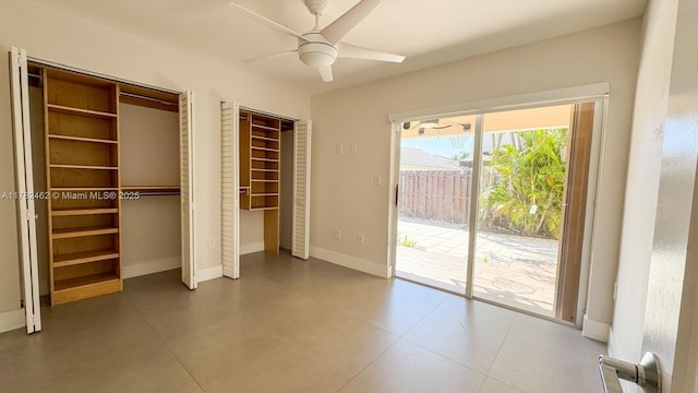 unfurnished bedroom featuring access to exterior, a ceiling fan, two closets, and baseboards
