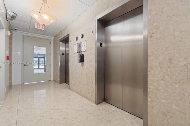 2100 Sans Souci Blvd Unit A1509, North Miami, FL 33181 - corridor featuring light tile patterned flooring, elevator, and tile walls