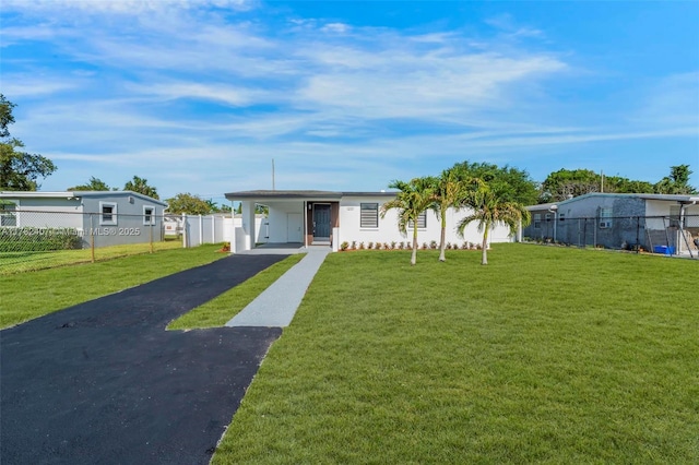 view of front of property with driveway, a front yard, fence, and an attached carport