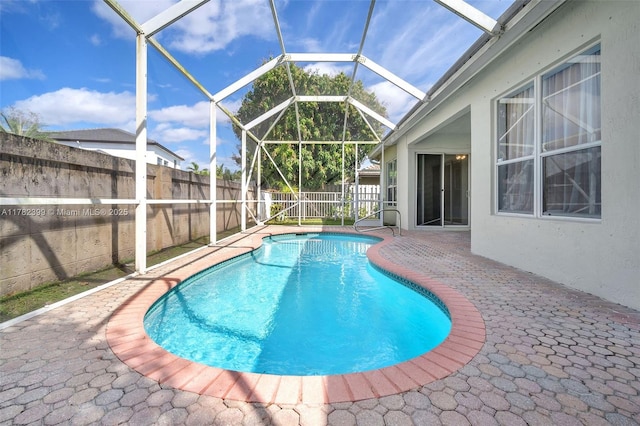 view of swimming pool with a patio, a fenced backyard, glass enclosure, and a fenced in pool