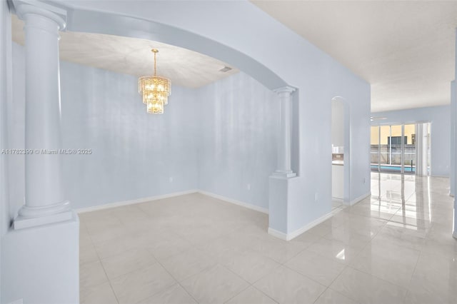 tiled empty room with visible vents, baseboards, ornate columns, arched walkways, and a notable chandelier
