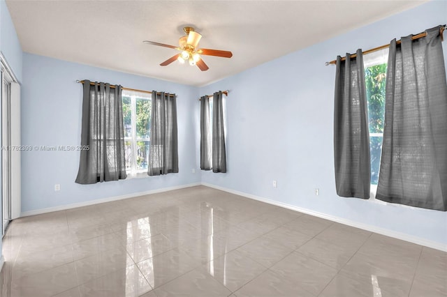 tiled spare room featuring baseboards and a ceiling fan