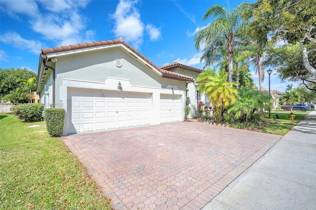 view of front facade with decorative driveway, a tile roof, a front lawn, and stucco siding
