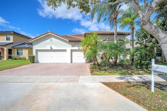 mediterranean / spanish home featuring a tiled roof, decorative driveway, an attached garage, and stucco siding