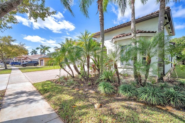 view of side of property with decorative driveway, a tile roof, and stucco siding
