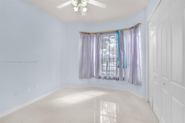 spare room featuring light tile patterned floors, baseboards, and ceiling fan