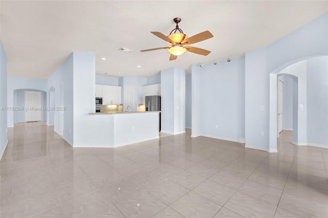 unfurnished living room featuring visible vents, baseboards, ceiling fan, arched walkways, and light tile patterned floors
