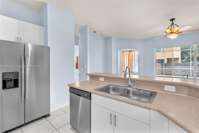 kitchen with appliances with stainless steel finishes, track lighting, a sink, white cabinetry, and light tile patterned floors