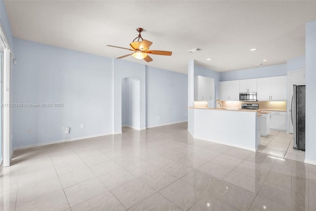 kitchen with light tile patterned floors, arched walkways, stainless steel appliances, and open floor plan