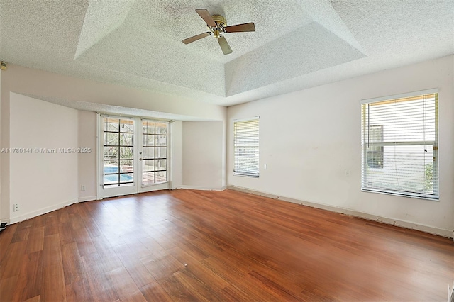 empty room with plenty of natural light, baseboards, a ceiling fan, and wood finished floors