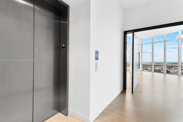 851 NE 1st Ave Ph 5500, Miami, FL 33132 - hallway with elevator, light wood-style floors, expansive windows, and baseboards