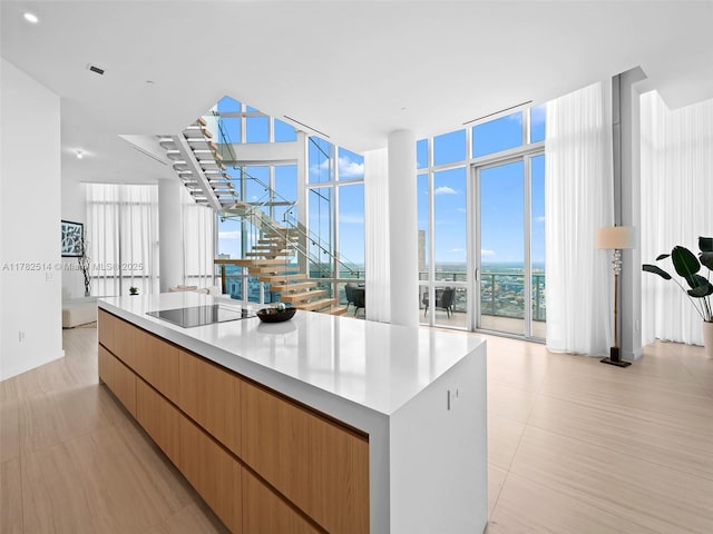 851 NE 1st Ave Ph 5500, Miami, FL 33132 - kitchen featuring black electric stovetop, light countertops, a kitchen island, a wall of windows, and modern cabinets