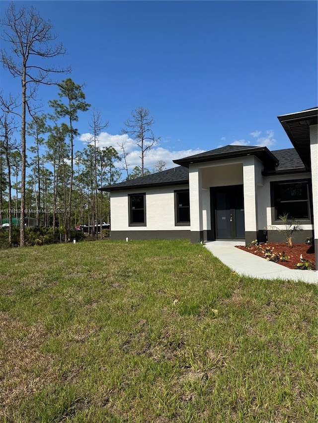 1316 Broadway Ave, Lehigh Acres, FL 33972 - back of property with stucco siding and a yard