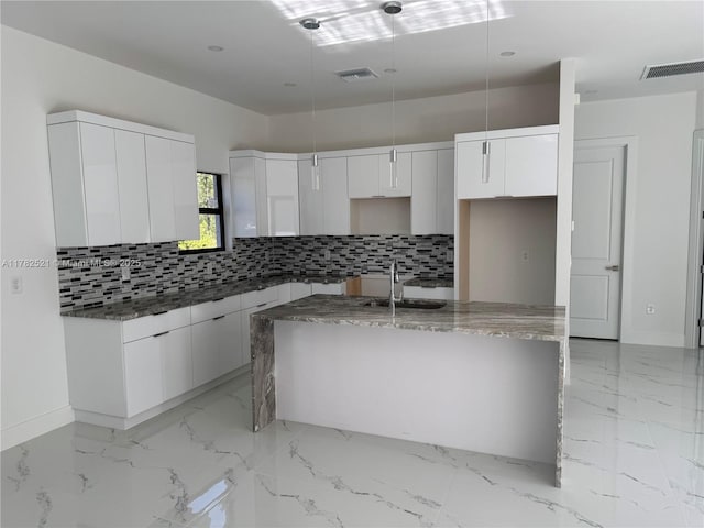 1316 Broadway Ave, Lehigh Acres, FL 33972 - kitchen featuring a sink, tasteful backsplash, a kitchen island with sink, and baseboards