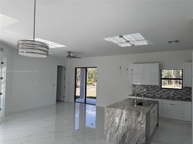 1316 Broadway Ave, Lehigh Acres, FL 33972 - kitchen featuring modern cabinets, light marble finish floors, a sink, backsplash, and white cabinets