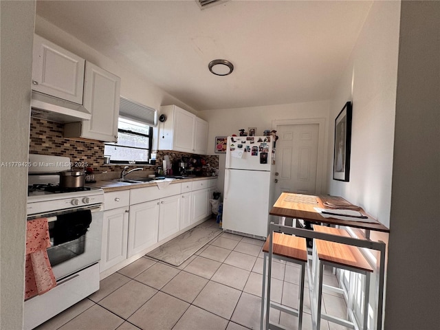 kitchen with white cabinets, under cabinet range hood, backsplash, a sink, and white appliances
