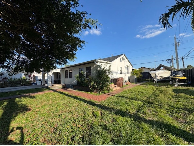 view of front of home featuring stucco siding, a front lawn, and fence
