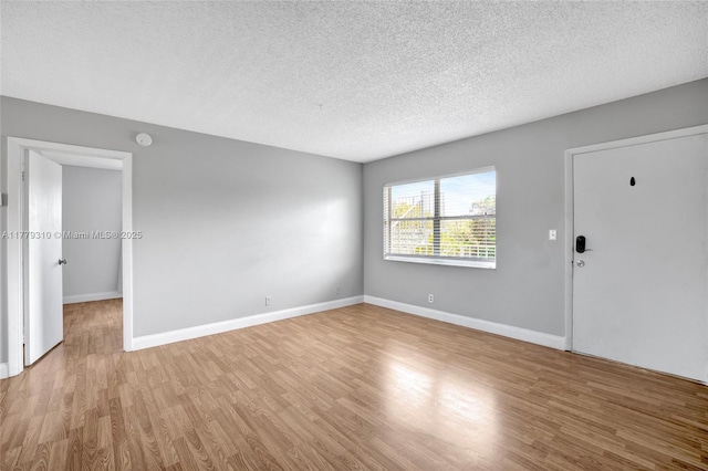 609 NE 13th Ave Unit 301, Fort Lauderdale, FL 33304 - unfurnished living room with light wood-style floors, baseboards, and a textured ceiling