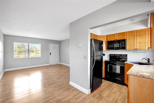 609 NE 13th Ave Unit 301, Fort Lauderdale, FL 33304 - kitchen with light stone countertops, light wood-style flooring, black appliances, a sink, and open floor plan