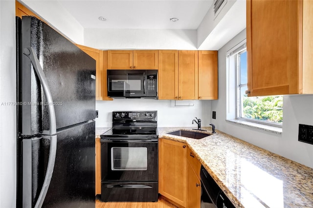 609 NE 13th Ave Unit 301, Fort Lauderdale, FL 33304 - kitchen featuring light wood-type flooring, a sink, black appliances, and light stone counters