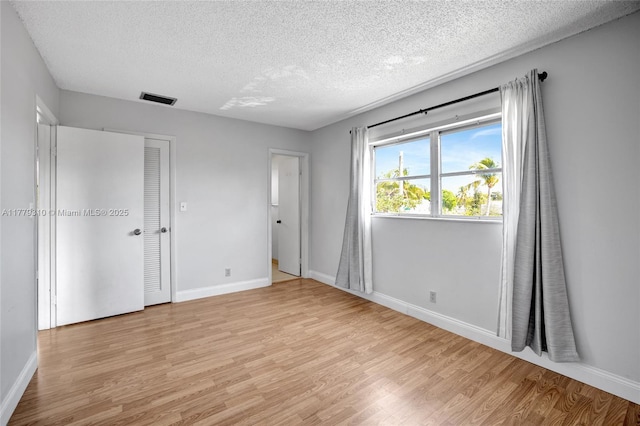 609 NE 13th Ave Unit 301, Fort Lauderdale, FL 33304 - unfurnished bedroom with visible vents, baseboards, light wood-style floors, and a textured ceiling
