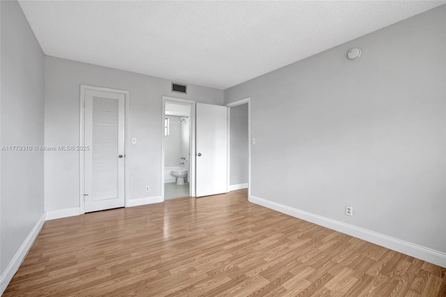 609 NE 13th Ave Unit 301, Fort Lauderdale, FL 33304 - unfurnished bedroom featuring light wood-style flooring, baseboards, visible vents, and ensuite bath