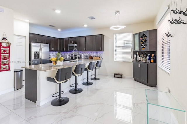 10572 W 35th Way, Hialeah, FL 33018 - kitchen featuring stainless steel appliances, dark brown cabinets, a breakfast bar area, light stone countertops, and a peninsula