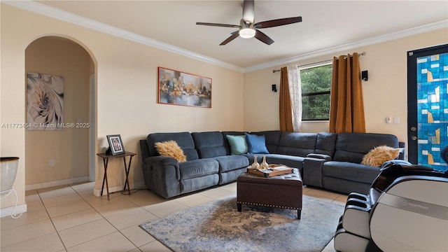 living room with baseboards, ornamental molding, light tile patterned floors, a ceiling fan, and arched walkways