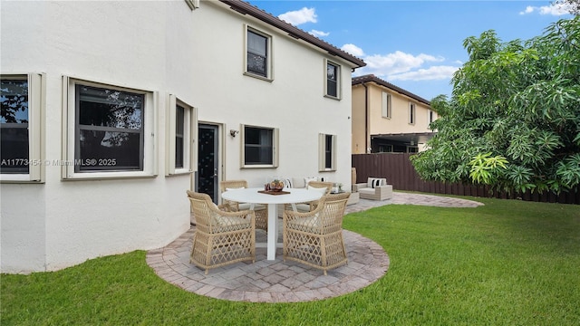 rear view of property with a patio area, stucco siding, fence, and a lawn