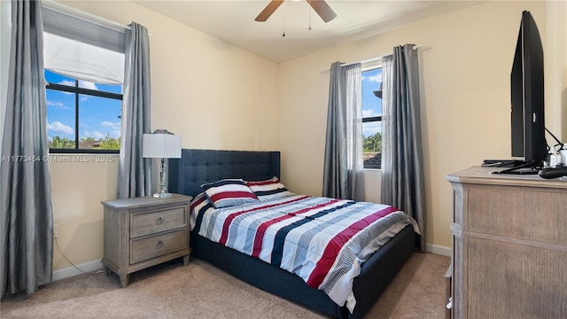 bedroom featuring light colored carpet, baseboards, and ceiling fan