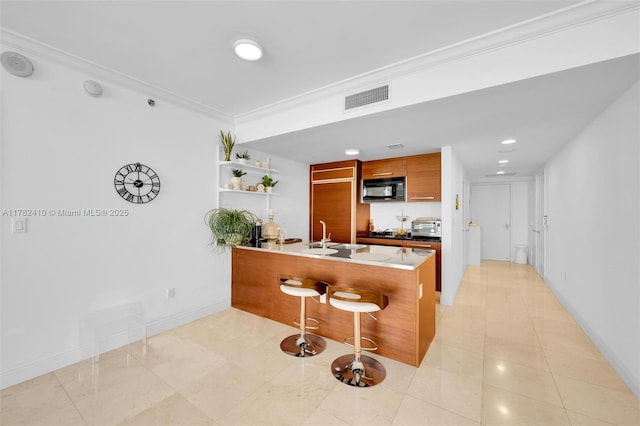 1850 S Ocean Dr Unit 1709, Hallandale Beach, FL 33009 - kitchen with black microwave, brown cabinetry, a peninsula, ornamental molding, and visible vents