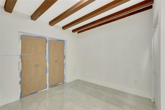 unfurnished room featuring beamed ceiling and baseboards