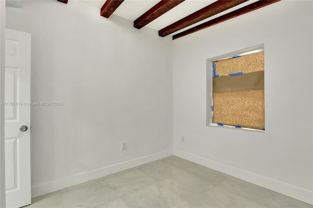 empty room featuring baseboards and beam ceiling