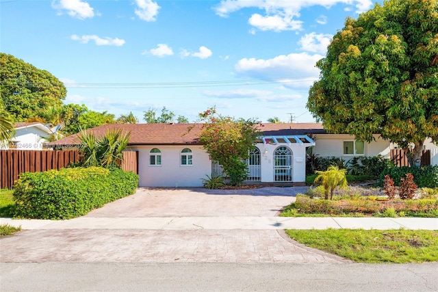 ranch-style home featuring driveway, stucco siding, and fence