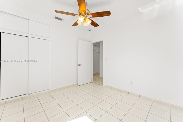 unfurnished bedroom featuring light tile patterned flooring, a closet, visible vents, and a ceiling fan
