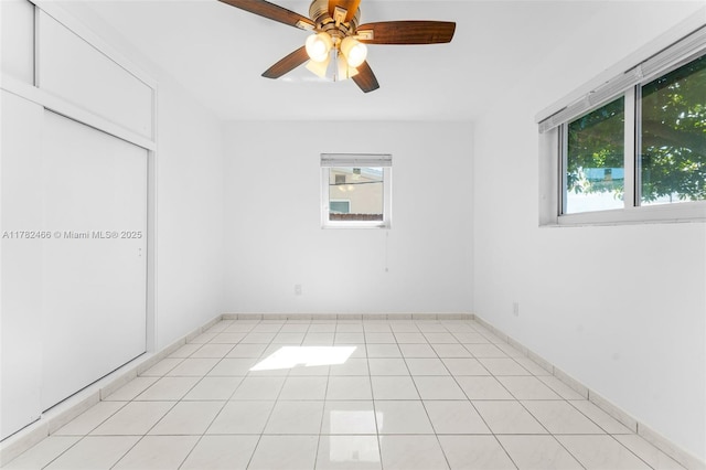 empty room with a ceiling fan and light tile patterned floors