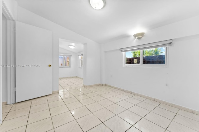 unfurnished room featuring vaulted ceiling and light tile patterned floors