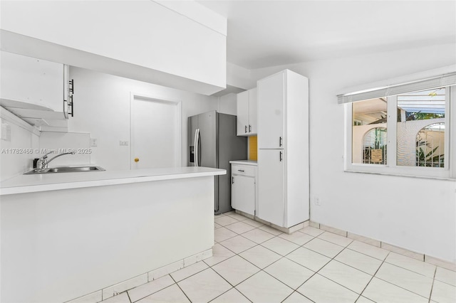 kitchen featuring light countertops, stainless steel refrigerator with ice dispenser, white cabinetry, and a sink