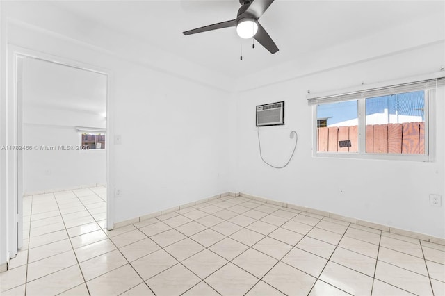 empty room featuring light tile patterned floors, an AC wall unit, ceiling fan, and a healthy amount of sunlight