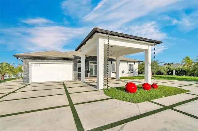 view of front of house featuring concrete driveway, french doors, stone siding, and an attached garage