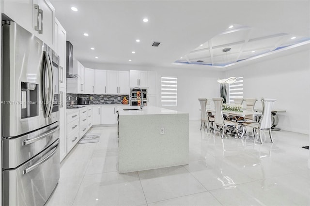 kitchen featuring recessed lighting, stainless steel refrigerator with ice dispenser, wall chimney exhaust hood, coffered ceiling, and a sink